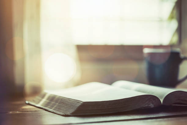 Open Bible on a desk illuminated by window light.